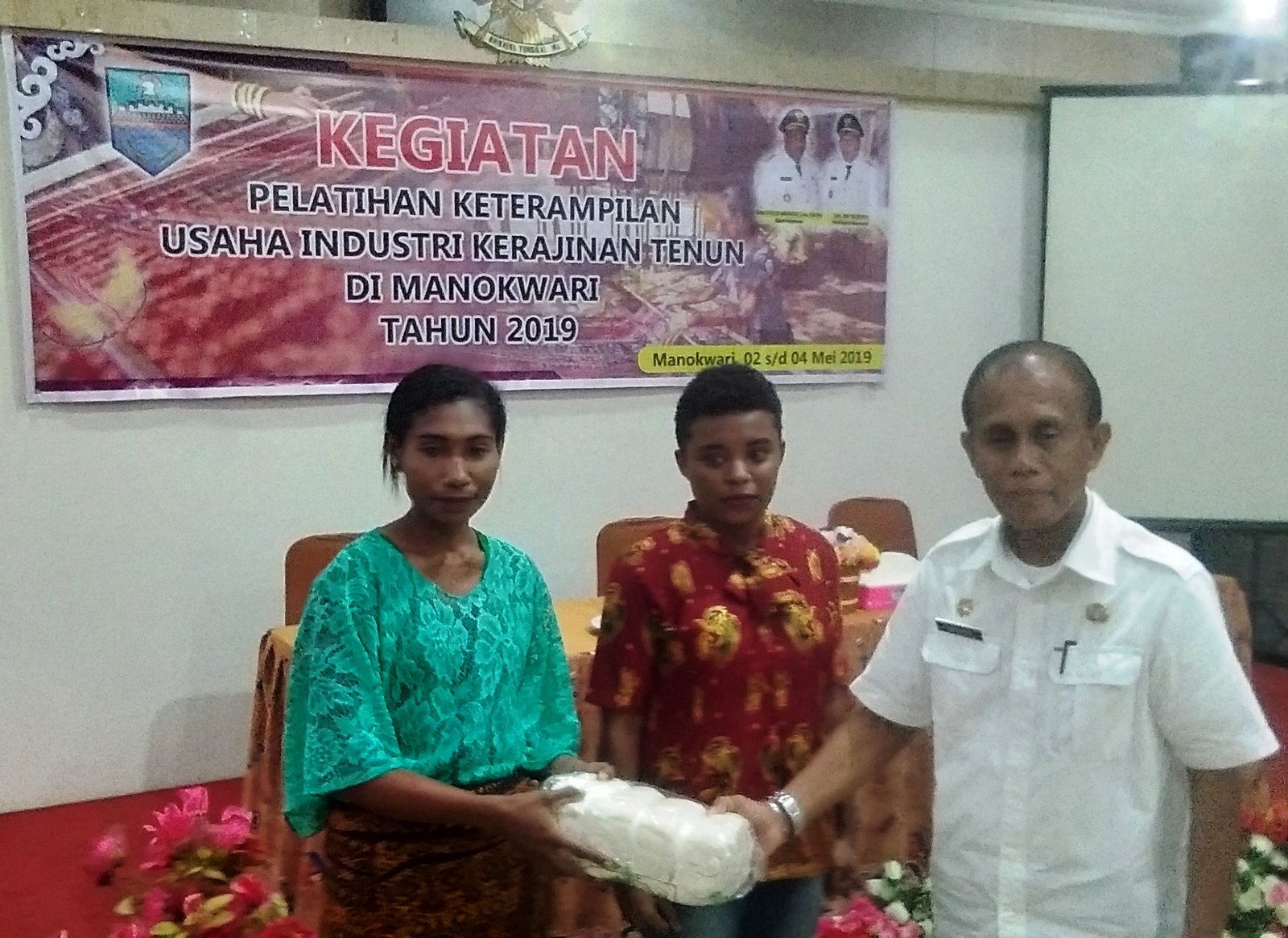 Sekda Kabupaten Manokwari menyerahkan secara simbolis bahan baku membuat kain tenun NTT kepada perwakilan peserta pelatihan Kerajinan Tenun Manokwari