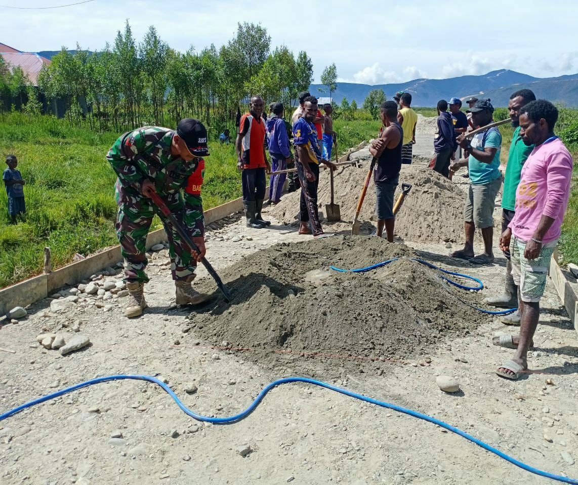Babinsa 06 Anggi Kodim 1801 Manokwari saat membantu warga dalam pekerjaan pengecoran jalan
