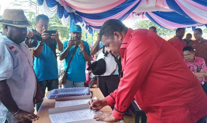 Bupati Demas Mandacan saat menandatangani berita acara penyerahan sertifikat lahan plasma ke 11 Poktan di Kampung Wasegi Indah, Distrik Prafi