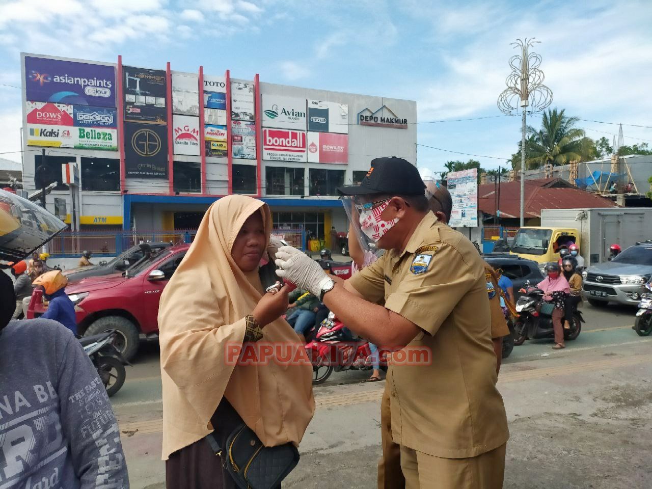 Plh. Bupati Manokwari Edi Budoyo memakaikan masker kepada salah seorang warga yang melintask di Jalan Trikora Wosi