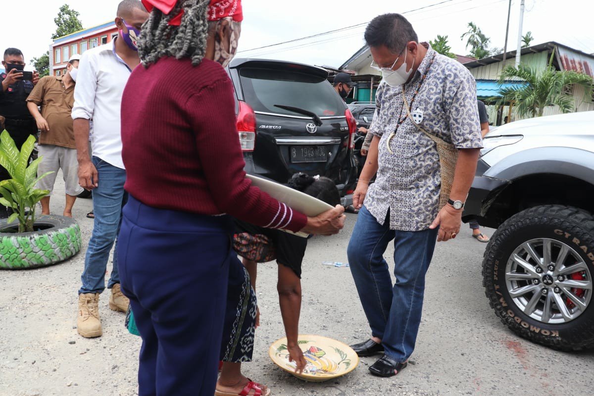 Kandidat Wakil Bupati Manokwari Edi Budoyo saat disambut dengan prosesi adat injak piring oleh warga Kompleks Kali Dingin