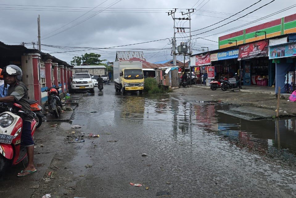 Genangan air di atas badan jalan akibat saluran air atau drainase di areal Pasar Wosi tersumbat sampah