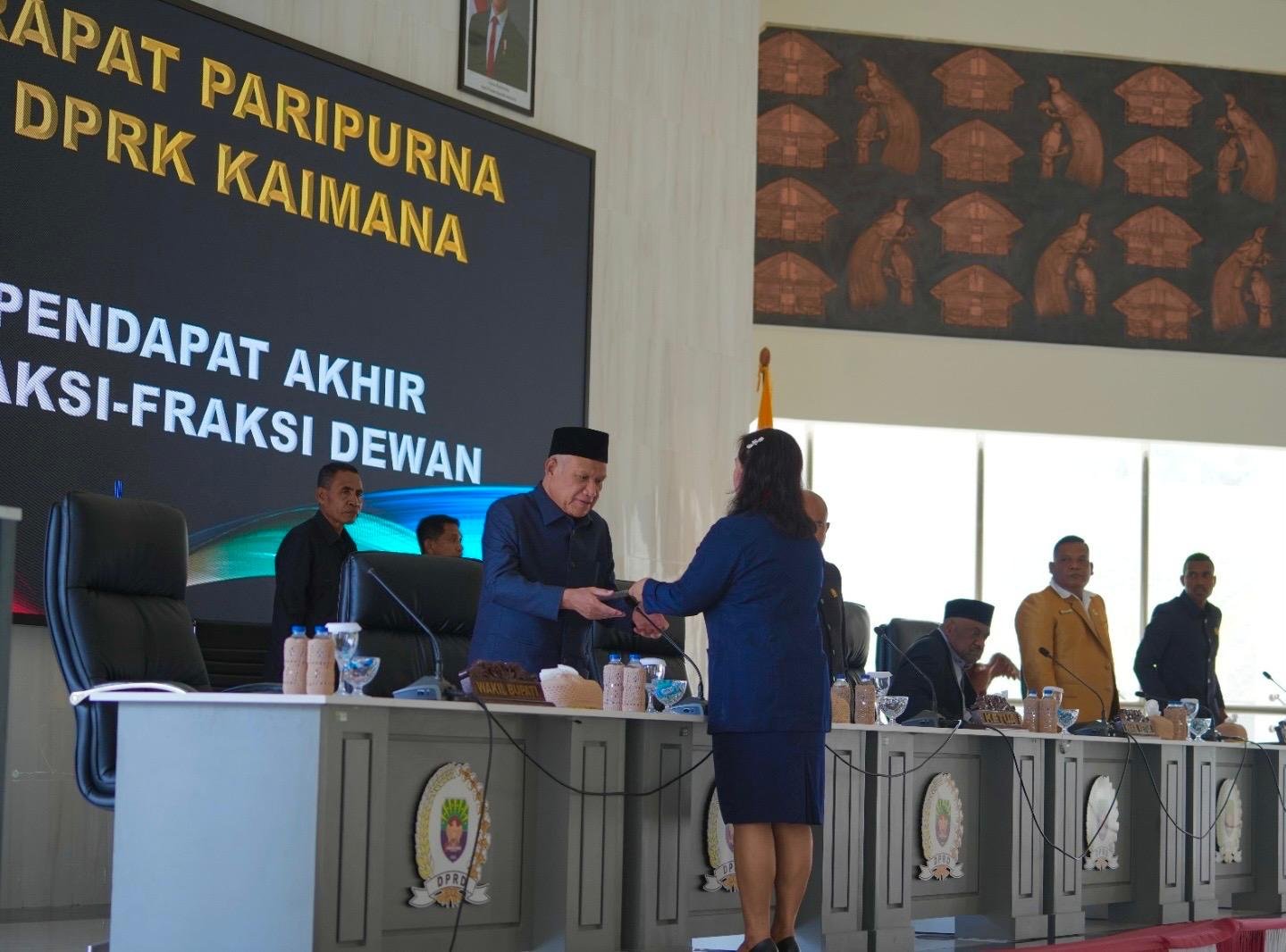 Bupati Kaimana, Drs. Hasan Achmad, menerima pandangan akhir fraksi dari salah satu anggota DPRK Kaimana pada rapat paripurna di Auditorium DPRK Kaimana,